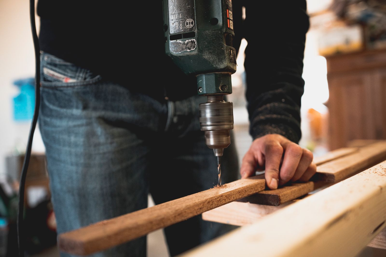 Craftsman drilling a hardwood rail on the workbench